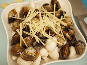 蛤犡吐沙洗淨處理後，直接鋪在菇上，接著灑上薑絲，加一湯匙米酒。