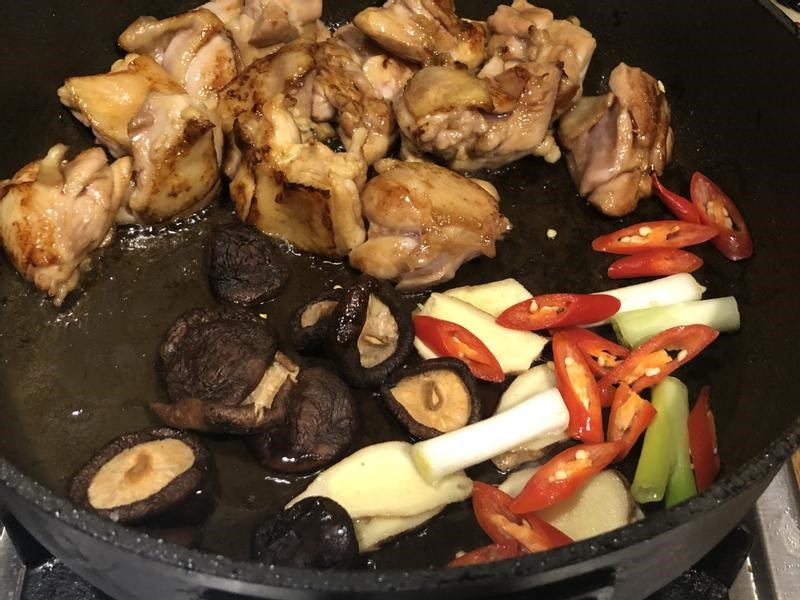 雞腿肉煎至金黃後，加入薑片、蔥白段、辣椒片爆香，跟雞腿肉一起拌炒。