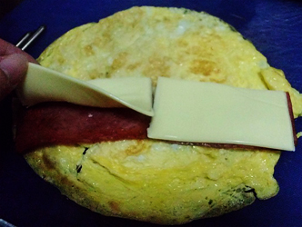 將火腿煎熟和起士片分別對切，放在蛋皮上。